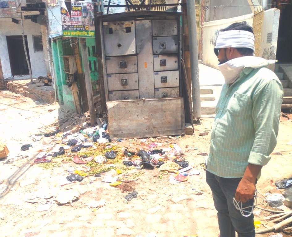 जौनपुर में कूड़े के ढेर के पास विद्युत लाइन पर कार्य करते बिजली विभाग के कर्मचारी